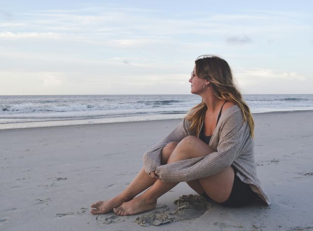 Mujer sentada en la playa - contenta con tus decisiones